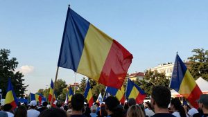 Steagul României flutură în fața mulțimilor animate.